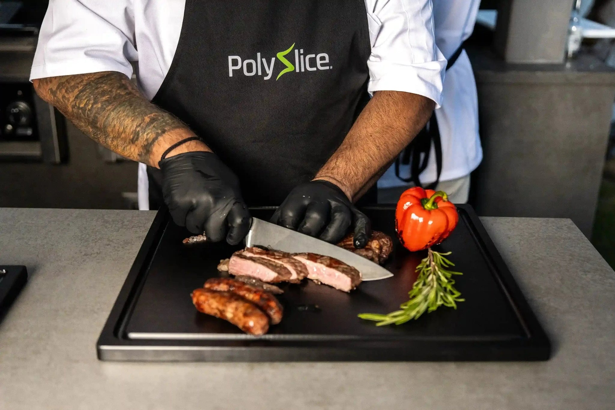 Person cutting meat on a black cutting board with PolySlice apron