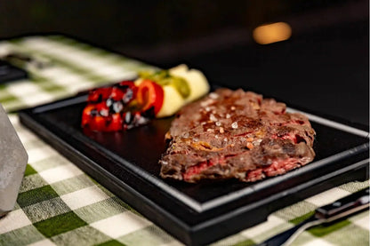 Close-up detail of a juicy steak being served on a Black PolySlice BBQ HDPE Plate - Non-porous and easy to clean material.
