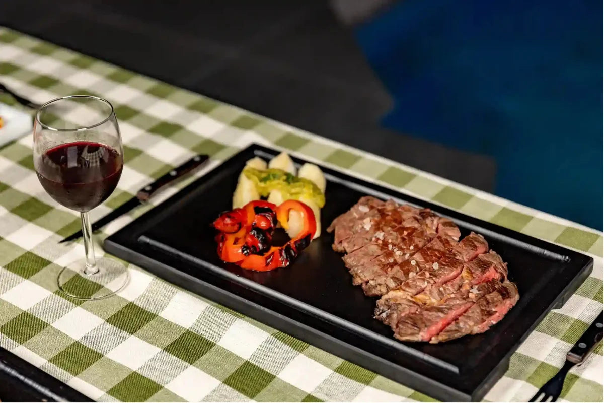 Premium Black PolySlice BBQ Serving HDPE Plate with grilled steak and wine - Stylish and durable dinner presentation.