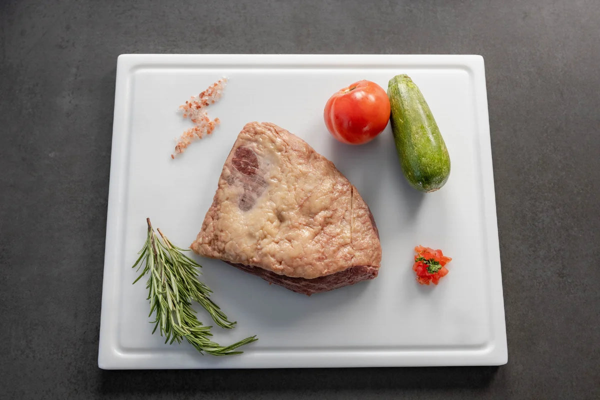 Raw pork belly slices being prepared on a White cutting board