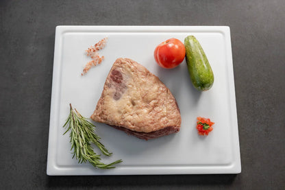 Raw pork belly slices being prepared on a White cutting board